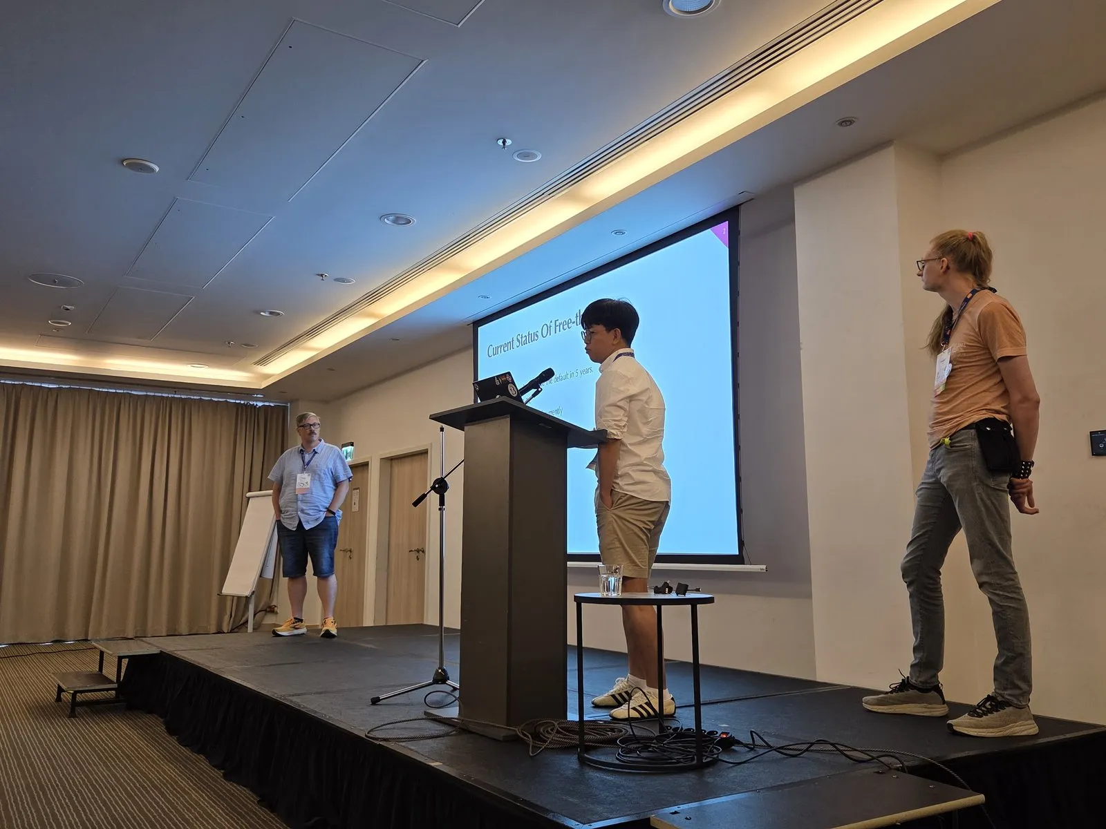 Donghee Na presenting at the lectern with Tobias Wrigstad and Fridtjof Stoldt standing on stage
